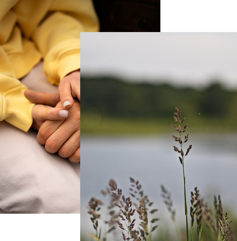 Couple holding hands outdoors by a lake with plants in foreground.